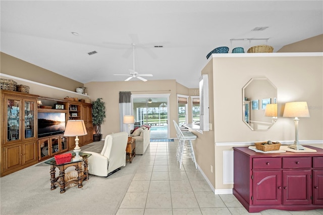 living area featuring light tile patterned flooring, a ceiling fan, visible vents, baseboards, and lofted ceiling