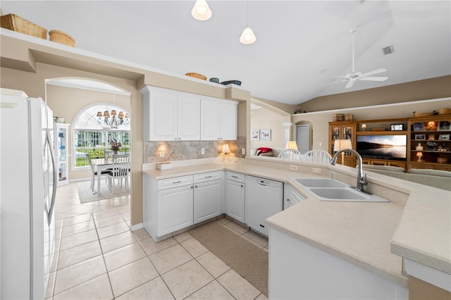 kitchen featuring decorative backsplash, a sink, light countertops, vaulted ceiling, and white appliances