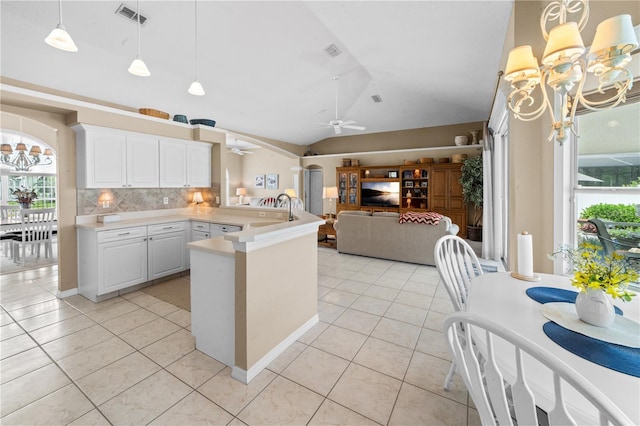 kitchen with light tile patterned flooring, visible vents, vaulted ceiling, a peninsula, and light countertops
