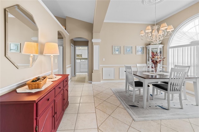dining room with light tile patterned flooring, a notable chandelier, crown molding, arched walkways, and wainscoting