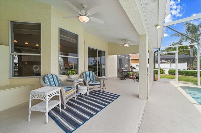 view of patio with a ceiling fan, an outdoor pool, and glass enclosure