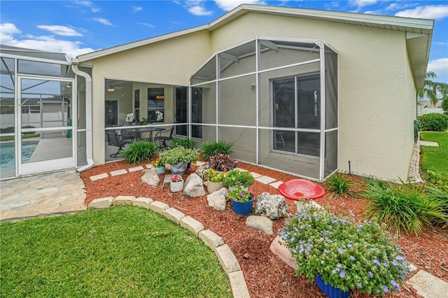 back of property with a lanai, stucco siding, and a patio area