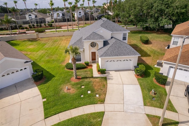 view of front facade with a garage, stucco siding, a shingled roof, driveway, and a residential view