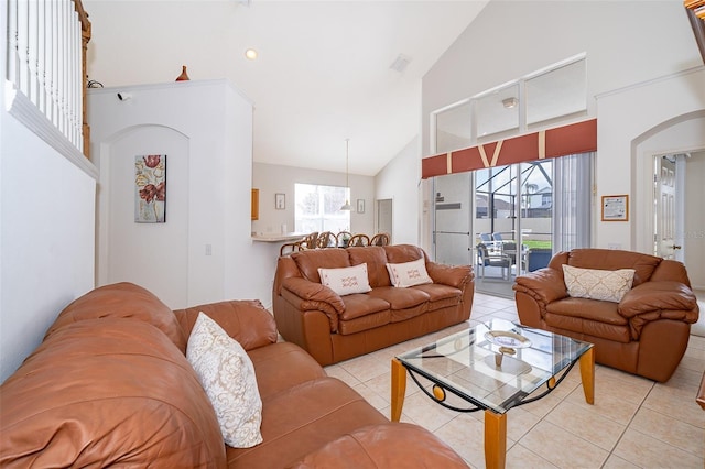 living room featuring light tile patterned floors, high vaulted ceiling, arched walkways, and visible vents