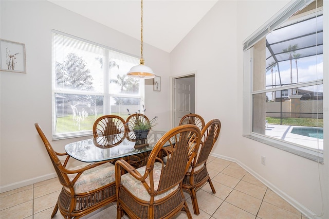 dining area featuring light tile patterned flooring, baseboards, and high vaulted ceiling