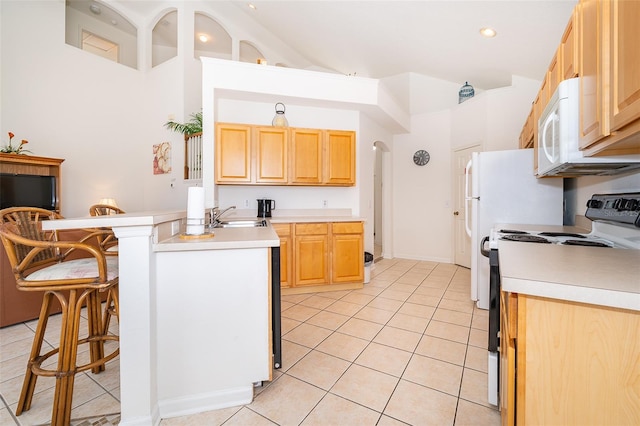 kitchen featuring range with electric stovetop, light brown cabinetry, arched walkways, light tile patterned floors, and light countertops