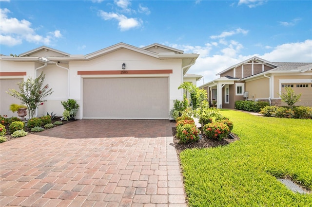 view of front of property featuring stucco siding, decorative driveway, a front yard, and an attached garage