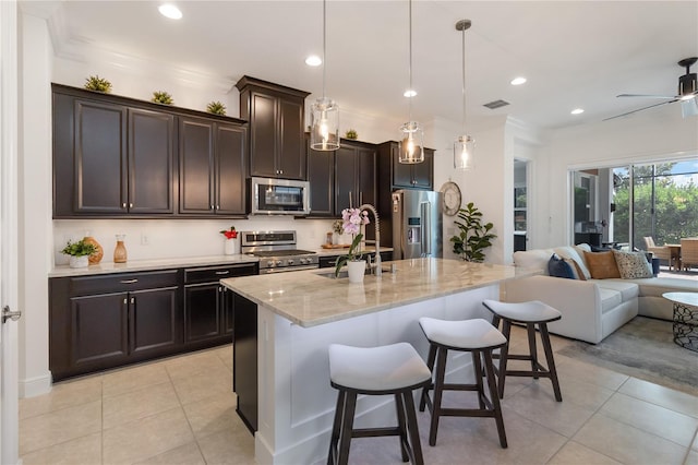 kitchen with appliances with stainless steel finishes, light tile patterned flooring, open floor plan, and a sink