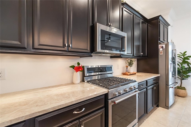 kitchen with appliances with stainless steel finishes, light tile patterned floors, light stone counters, and crown molding