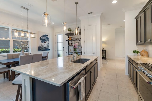 kitchen with a kitchen island with sink, a sink, stainless steel appliances, visible vents, and hanging light fixtures