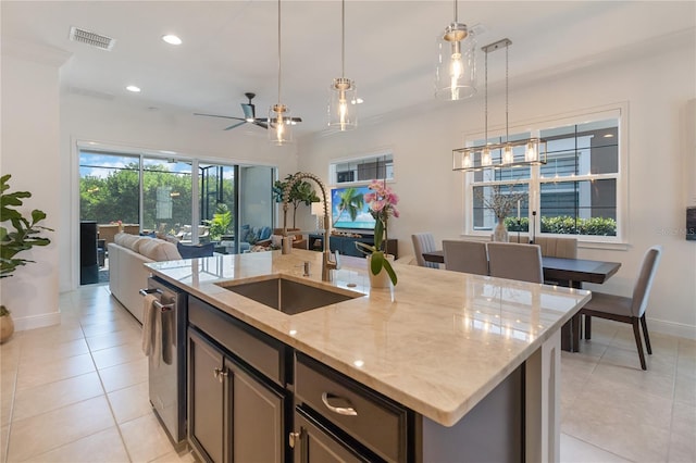 kitchen featuring stainless steel dishwasher, a sink, baseboards, open floor plan, and light tile patterned flooring