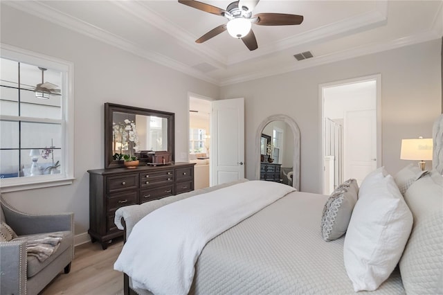 bedroom featuring light wood-style floors, a tray ceiling, crown molding, visible vents, and baseboards