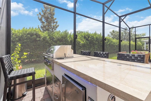 view of patio / terrace featuring a grill, glass enclosure, and exterior kitchen