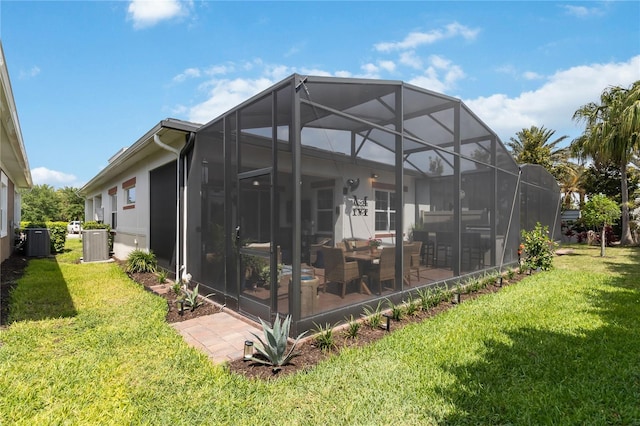 rear view of property with a patio, a lanai, cooling unit, and a yard