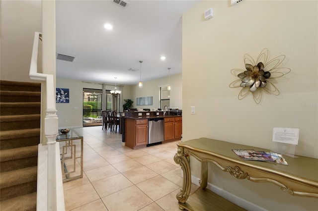 kitchen with light tile patterned floors, stainless steel dishwasher, dark countertops, visible vents, and a chandelier