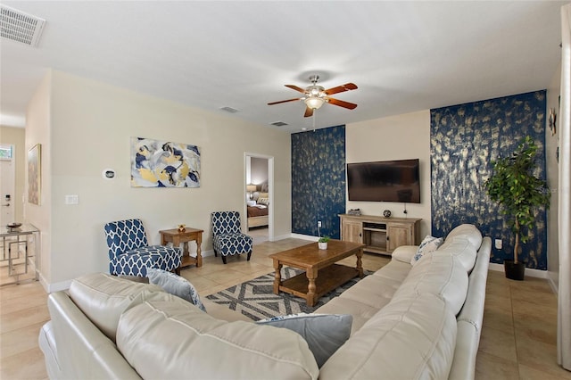tiled living room featuring baseboards, visible vents, a ceiling fan, and wallpapered walls
