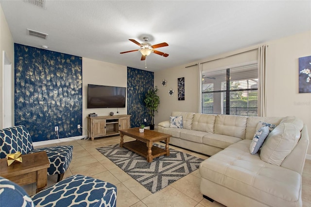 living room featuring tile patterned floors, wallpapered walls, an accent wall, ceiling fan, and visible vents