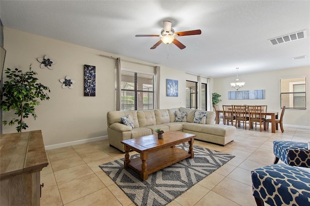 living room featuring ceiling fan with notable chandelier, visible vents, light tile patterned floors, and a wealth of natural light