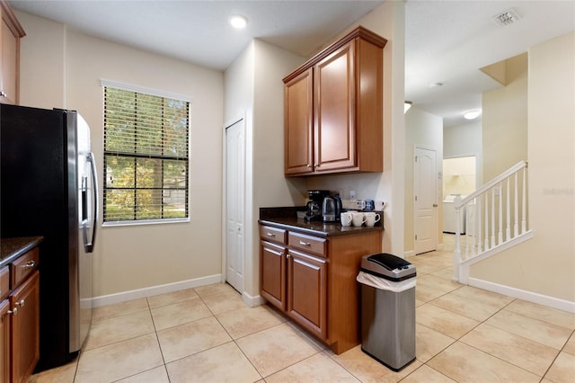 kitchen featuring light tile patterned floors, visible vents, freestanding refrigerator, and baseboards