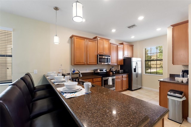kitchen with light tile patterned floors, appliances with stainless steel finishes, visible vents, a peninsula, and hanging light fixtures