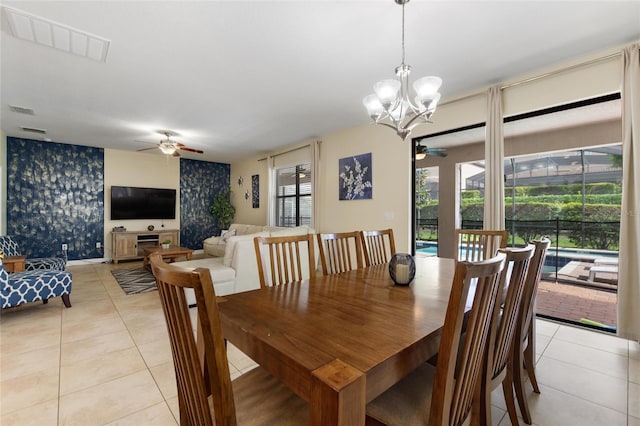 dining space with light tile patterned flooring, visible vents, wallpapered walls, and ceiling fan with notable chandelier