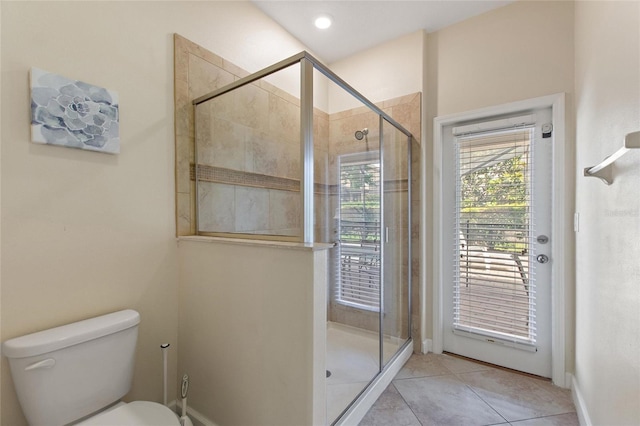 bathroom with toilet, a shower stall, tile patterned flooring, and baseboards