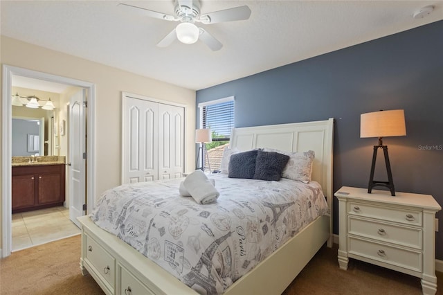 bedroom featuring a sink, ceiling fan, ensuite bathroom, a closet, and light carpet