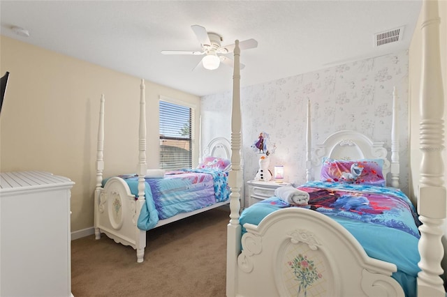 carpeted bedroom featuring visible vents, a ceiling fan, wallpapered walls, and baseboards