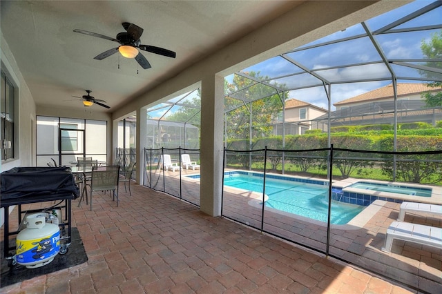 view of swimming pool featuring a patio, glass enclosure, a ceiling fan, and a pool with connected hot tub