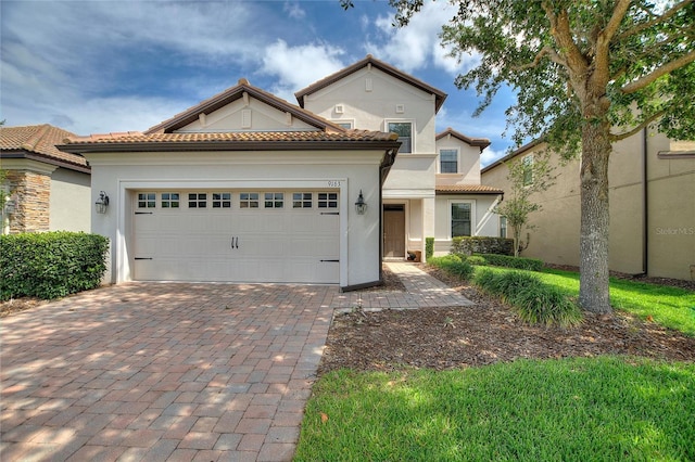 view of front of house featuring an attached garage, decorative driveway, stucco siding, and a tiled roof