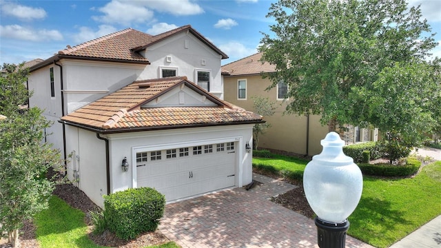 mediterranean / spanish home featuring decorative driveway, stucco siding, and a tiled roof