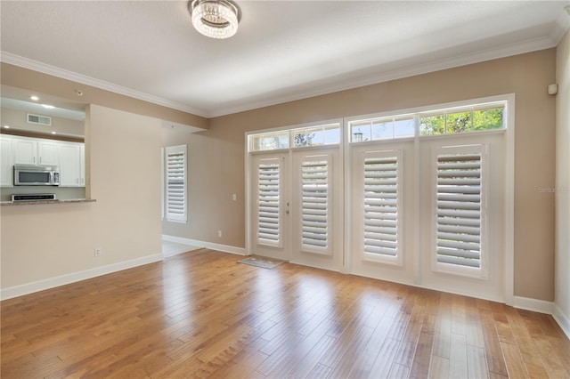 unfurnished living room with visible vents, baseboards, crown molding, and light wood-type flooring