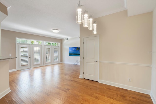 unfurnished room featuring baseboards, light wood-style flooring, crown molding, and a chandelier