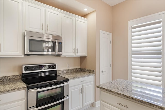 kitchen with light stone counters, white cabinetry, and appliances with stainless steel finishes