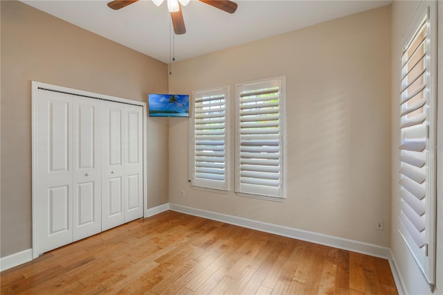 unfurnished bedroom featuring a ceiling fan, baseboards, light wood finished floors, and a closet