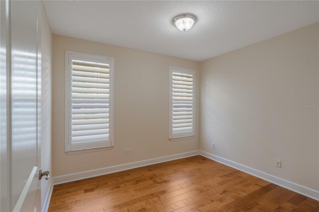 spare room featuring baseboards and light wood-style floors