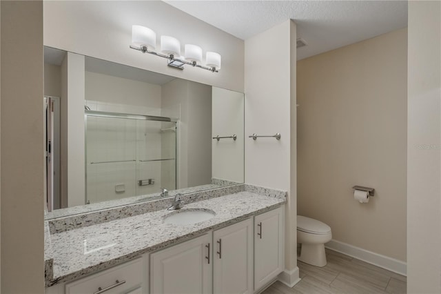 bathroom featuring vanity, toilet, baseboards, and a stall shower