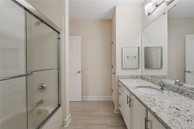 full bath with baseboards, enclosed tub / shower combo, and vanity