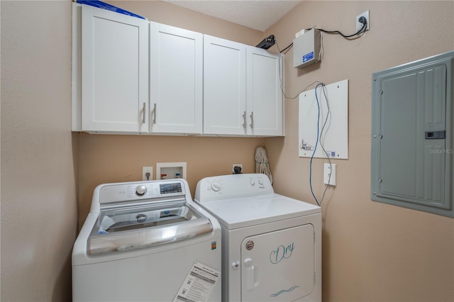 clothes washing area featuring separate washer and dryer, electric panel, and cabinet space