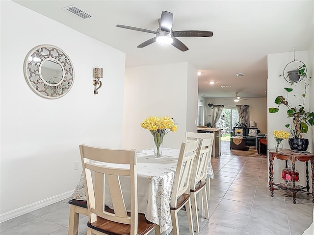 dining space with baseboards, visible vents, a ceiling fan, and light tile patterned flooring
