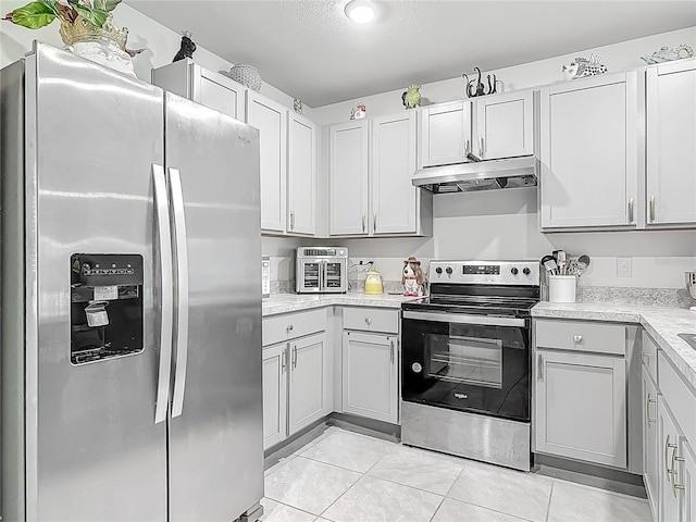kitchen featuring stainless steel appliances, light tile patterned flooring, under cabinet range hood, and light countertops