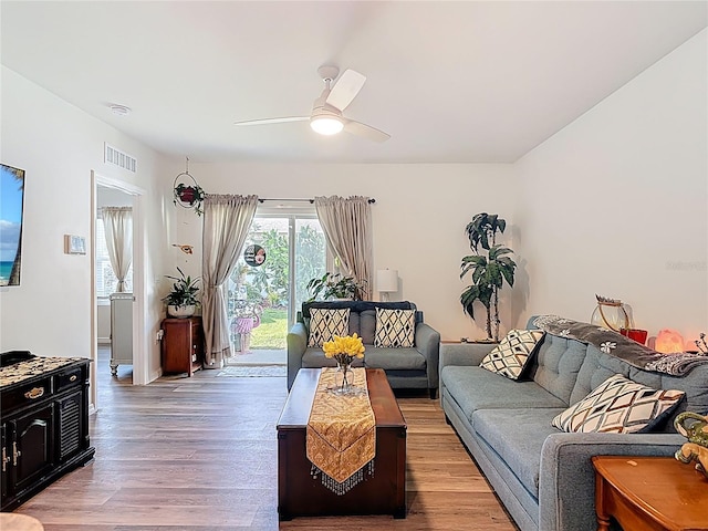 living room featuring visible vents, light wood-type flooring, and a ceiling fan
