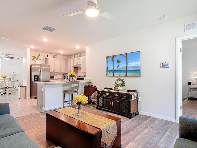 living area with ceiling fan, light wood-style flooring, and visible vents