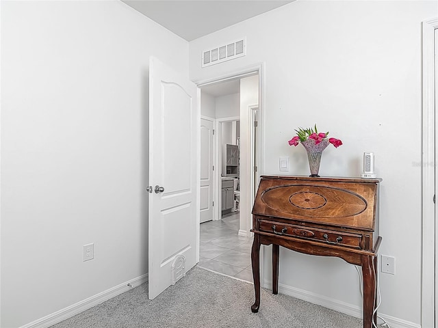 hall featuring visible vents, light carpet, and baseboards