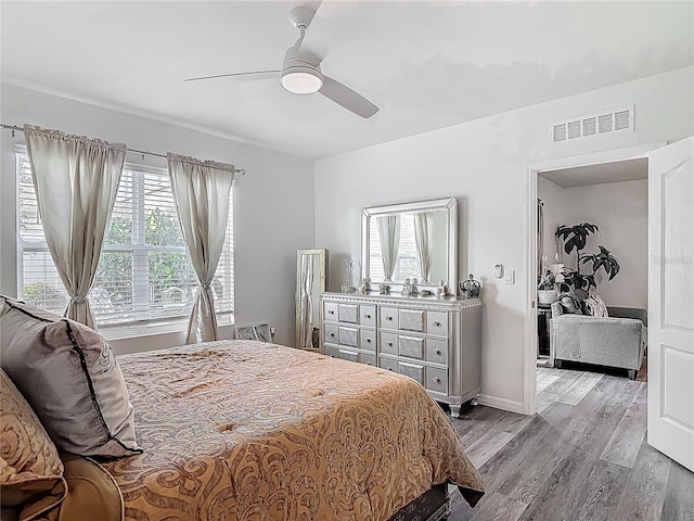 bedroom with a ceiling fan, visible vents, and wood finished floors