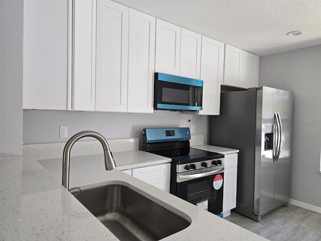 346 NW 24th Ave, Ocala, FL 34475 - kitchen with a sink, light stone counters, white cabinetry, a textured ceiling, and appliances with stainless steel finishes