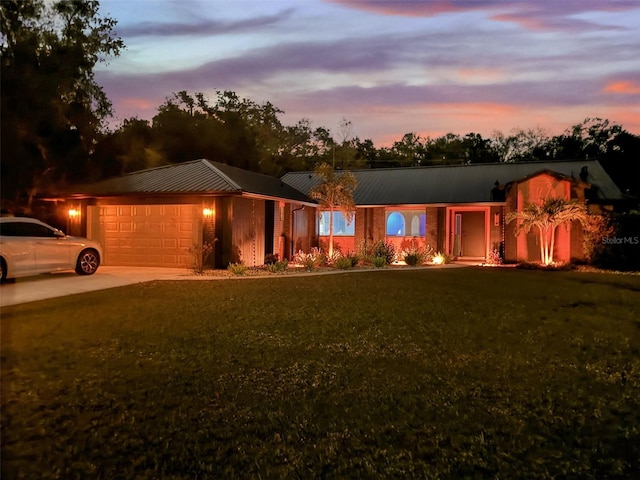 view of front of property featuring a garage, a front lawn, metal roof, and concrete driveway