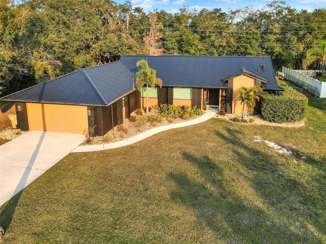 view of front of home with driveway, metal roof, a front yard, a garage, and fence