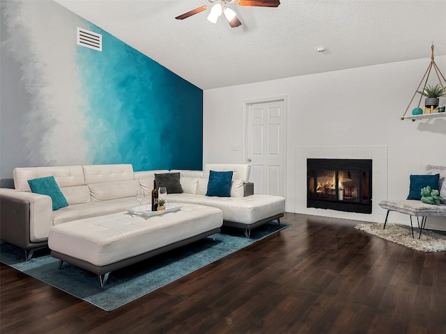 living room featuring a fireplace, a ceiling fan, wood finished floors, vaulted ceiling, and visible vents