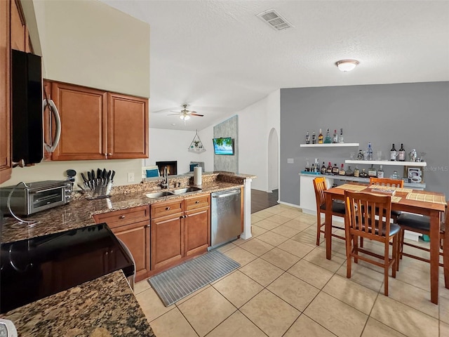kitchen featuring brown cabinets, appliances with stainless steel finishes, a sink, a ceiling fan, and visible vents